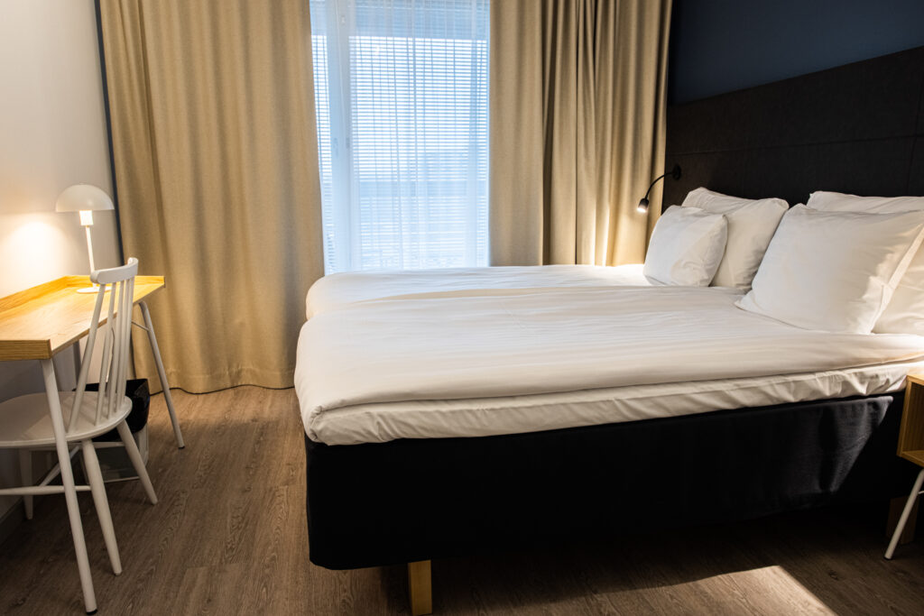 Viihtyisä makuuhuone suurella sängyllä ja värikkäillä tyynyillä huoneistohotelli Hotel Mattsissa Espoossa.